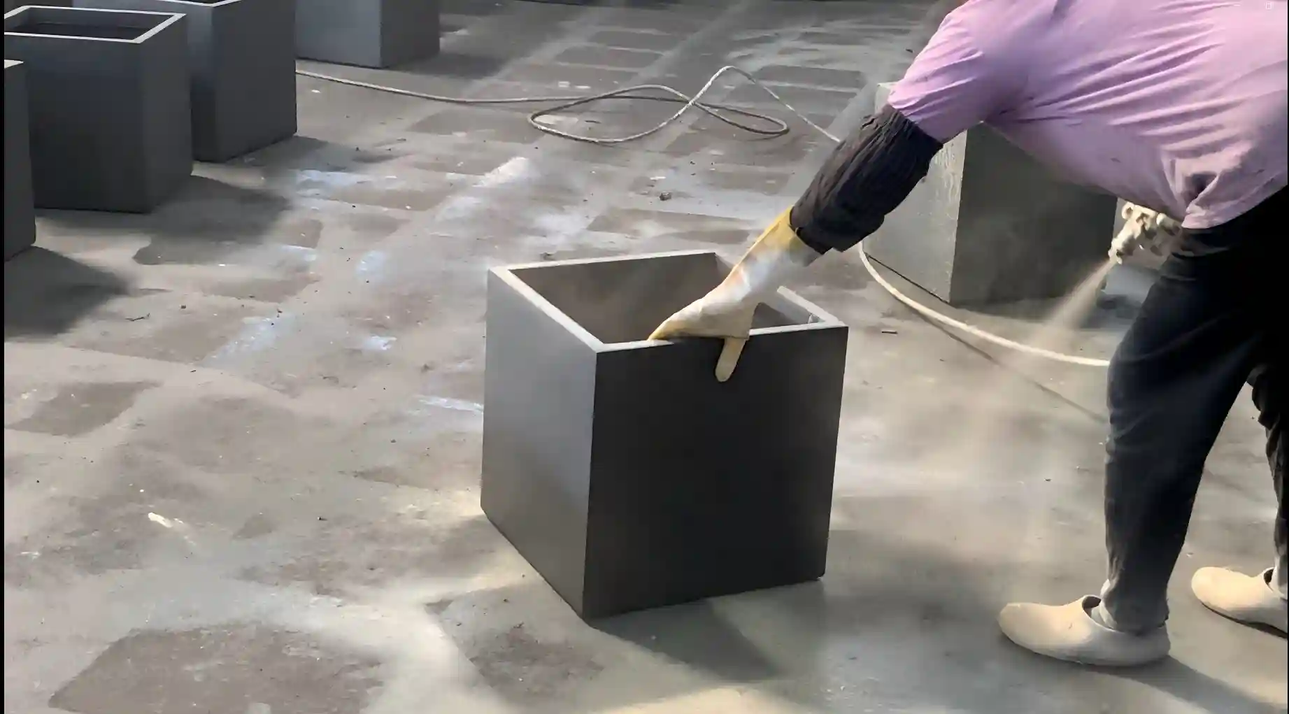 Worker applying fiber reinforced cement material during GRC planter production